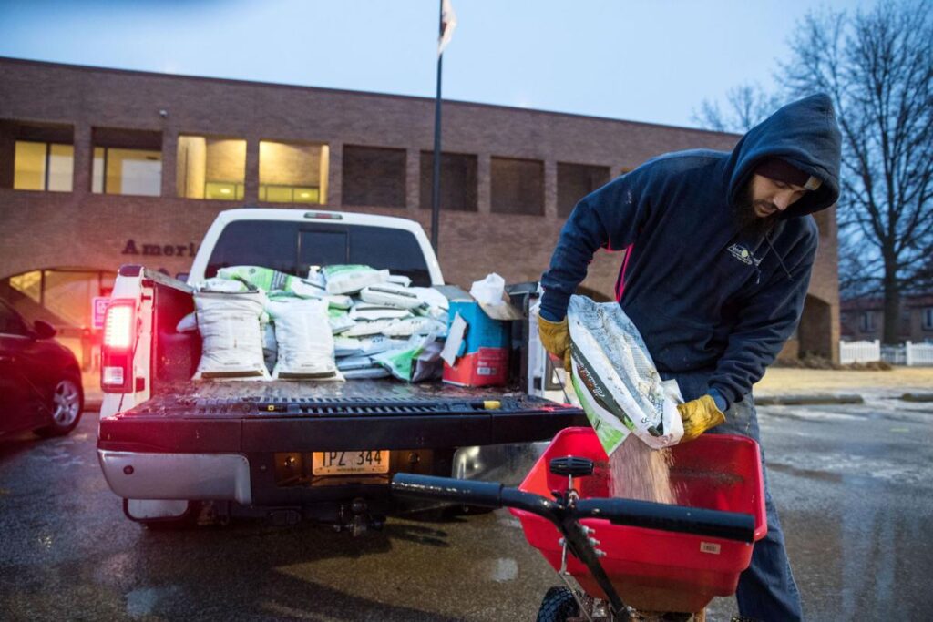 Man pouring ice pretreatment from bag into wheelbarrow.