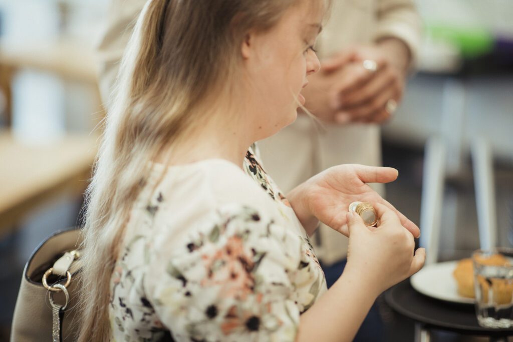 Teenage girl with Down syndrome being served at outdoor cafe.