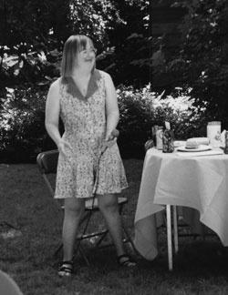 Black and white photo of Sandra Jensen standing outside by a table.