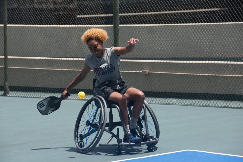 Woman in wheelchair playing pickleball during "Find Your Fun" Workshop.